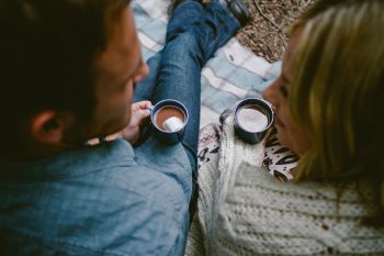 A couple sitting in the forest having a cup of hot chocolate